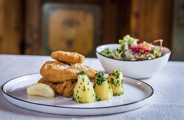 Nahaufname des Backhendls mit Zitrone, Petersilienkartoffeln und ein gemischter Salat als Beilage im Genussdorf Gmachl in Bergheim bei Salzburg