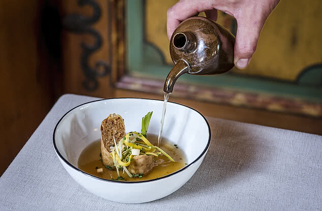Leckere Suppe mit Brot und frischen Kräutern, stilvoll serviert im Genussdorf Gmachl.